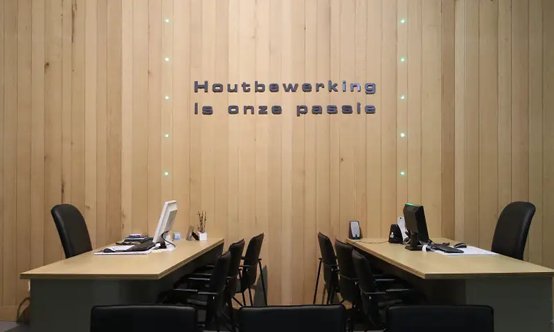 De adviesruimte in de toonzaal met houten wandbekleding en de tekst Houtbewerking is onze passie