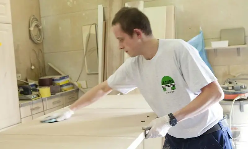 Schrijnwerker die een deurblad schuurt in het atelier van Jacobs Binnendeuren